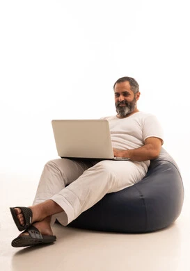 عقد إجتماع عمل عبر الإنترنت، تصفح برامج التواصل الاجتماعي، إستخدام الحاسوب المحمول لإنجاز المهام،  بورتريه لرجل عربي سعودي خليجي يرتدي سروال وفانيلا أبيض يجلس على كرسي بين باج يحمل جهاز اللابتوب، تطور التكنولوجيا والأجهزة التقنية، خلفية بيضاء