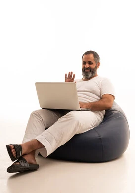 اجراء مكالمة فيديو، رفع كف اليد بتعابير السلام و التحية، إستخدام الحاسوب المحمول لإنجاز المهام،  بورتريه لرجل عربي سعودي خليجي يرتدي سروال وفانيلا أبيض يجلس على كرسي بين باج يحمل جهاز اللابتوب، تطور التكنولوجيا والأجهزة التقنية، خلفية بيضاء