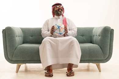 النظر الى شيء ما، الشغف برياضة كرة القدم ، المباريات والألعاب الرياضية، بورتريه لرجل عربي خليجي سعودي يرتدي الثوب الابيض و الشماغ يجلس على الاريكة يحمل بيده كرة قدم, خلفية بيضاء النظر الى شيء ما، الشغف برياضة كرة القدم ، المباريات والألعاب الرياضية، بورتريه لرجل عربي خليجي سعودي يرتدي الثوب الابيض و الشماغ يجلس على الاريكة يحمل بيده كرة قدم, خلفية بيضاء