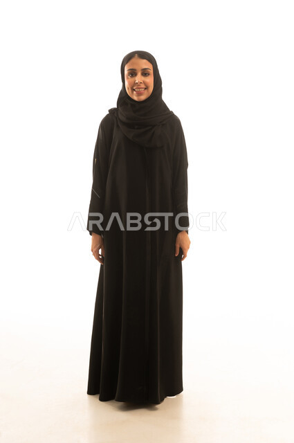 بورتريه خلفية بيضاء الجسم بالطول الكامل لامرأة عربية خليجية محجبة ترتدي عباءة سوداء ,الوقوف و الابتسام امام الكاميرا
