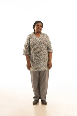 الوقوف امام الكاميرا و النظر الي شئ ما ,بورتريه خلفية بيضاء لعاملة منزلية افريقية سمراء البشرة ترتدي يونيفورم اللون الرمادى ,الجسم بالطول الكامل