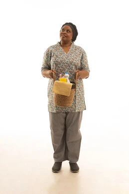 شغالة افريقية سمراء البشرة ترتدي يونيفورم باللون الرمادي تحمل مستلزمات نظافة المنزل داخل سلة القش ,بورتريه خلفية بيضاء الجسم بالطول الكامل ,النظر الى شئ ما