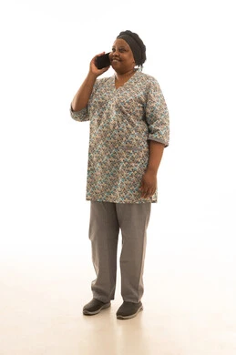 Making a phone call happily, an African housekeeper with dark skin wearing a gray uniform talking on the phone, full-length portrait with a white background.