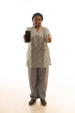 Thumbs up for approval and liking, an African housekeeper with dark skin wearing a gray uniform, showing a blank black mobile phone screen to the camera, full-length portrait with a white background.