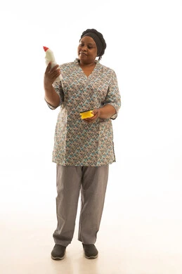 عاملة منزلية افريقية سمراء البشرة ترتدي يونيفورم رمادي اللون تحمل زجاجة من سائل غسيل الصحون و اسفنجة صفراء ,بورتريه الجسم بالطول الكامل ,خلفية بيضاء