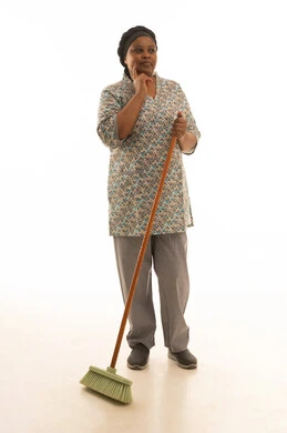 بورتريه خلفية بيضاء الجسم بالطول الكامل لشغالة منزلية افريقية سمراء البشرة ترتدي يونيفورم باللون الرمادي تحمل مكنسة يدوية ,التفكير في كيفية ممارسة العمل