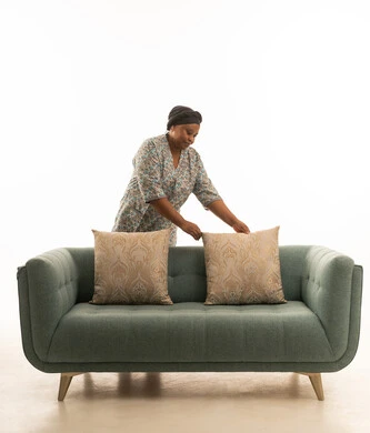 العمالة المنزلية المؤهلة ,بورتريه عاملةمنزلية افريقية سمراء البشرة ترتدي يونيفورم لون رمادي تمسك وسادة صغيرة ,بورتريه خلفية بيضاء الجسم بالطول الكامل