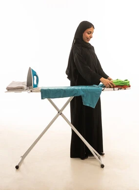 بورتريه امرأة عربية سعودية خليجية  محجبة  مبتسمة ترتدي عباءة سوداء تقوم بتصفيط الملابس و تنظيمها ,خلفية بيضاء الجسم بالطول الكامل