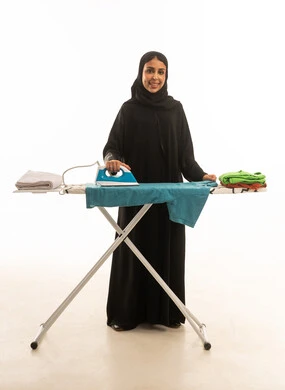 ابتسامة لسيدة عربية سعودية خليجية ترتدي عباءة سوداء تقوم بكى الملابس و ترتيبها, بورتريه للجسم بالطول الكامل خلفية بيضاء لقطة أمامية للكاميرا