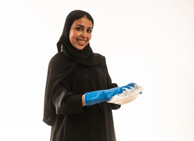 القيام بالاعمال المنزلية بسرور و ابتسامة,بورتريه لامرأة عربية سعودية خليجية تنظر للكاميرا ترتدي عباءة سوداء تقليدية ,بورتريه خلفية بيضاء