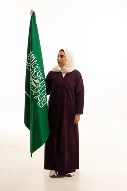 Love of the homeland and belonging to it, a portrait of a Saudi Arabian Gulf woman wearing a hijab and an abaya holding the flag, celebrating the anniversary of the Saudi National Day on the 8th of Rabi' al-Awwal, pride and honor in belonging to the Kingdom, full-body, white background.