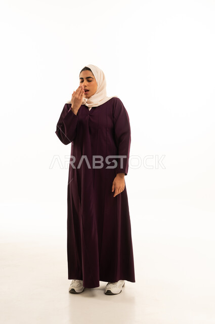 A portrait of a Saudi Arabian Gulf woman wearing a hijab and an abaya, showing expressions of laziness and lethargy, having stayed up late, full-body shot, with a white background.