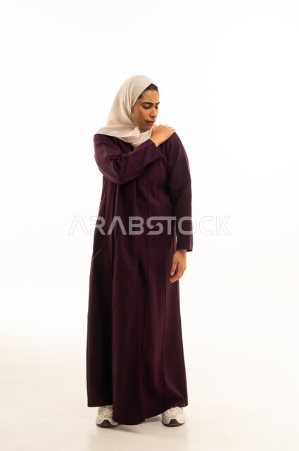 الشعور بالمرض والتعب، التهاب العضلات والمفاصل، الحاجه للعلاج وطلب المساعده, بورتريه لإمرأة خليجية سعودية محجبة ترتدى العباءة تضع يدها على كتفها بإيماءات تدل على الألم الشديد, الجسم بالطول الكامل, خلفية بيضاء