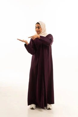A portrait of a Saudi Gulf woman wearing a hijab and an abaya, pointing to the palm of her hands, with her index finger indicating something specific, standing and looking at the camera with gestures of joy, full body, white background.