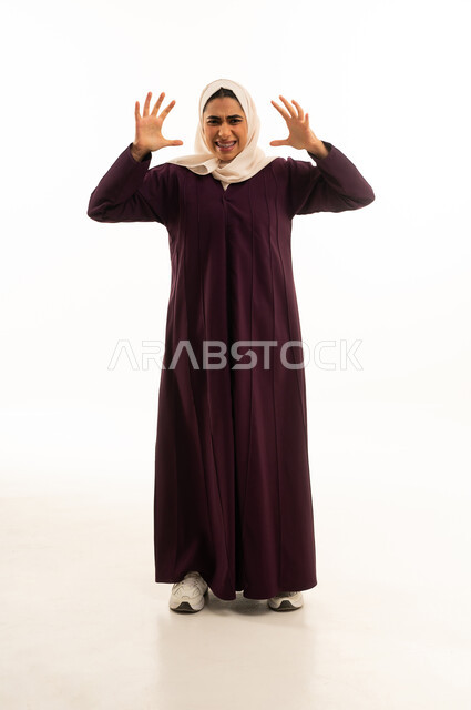 Expressions of crying, anger, and excitement, a portrait of a Saudi Gulf woman in a hijab wearing an abaya, raising her hands upwards with gestures of deep sorrow, full-body, white background.