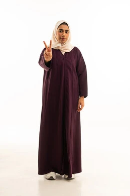 النجاح وتحقيق الأهداف, مفهوم السعادة بالوصول إلى الغايات, بورتريه لإمرأه عربيه خليجيه سعودية محجبه ترتدي العباءه ترفع يدها بإشارة النصر والقوة, إيماءات الفرح بالفوز والنصر, النظر إلى الكاميرا بتعابير السرور, الجسم بالطول الكامل, خلفية بيضاء