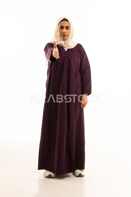 تعابير الموافقة و القبول ,النظر الى الكاميرا بإيماءات السرور, بورتريه لامراة عربية خليجية سعودية مبتسمة محجبة ترتدي العباءة  ترفع اصبع الابهام للاعلى بعلامة الامتياز و الجودة, خلفية بيضاء