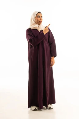 تحديد موقع معين بإيماءات البشاشة، بورتريه لامرأة عربيه خليجيه سعوديه مبتسمه محجبه ترتدي العباءة وترفع اصابعها وتشير الى شيء ما, النظر الى الاعلى بإيماءات السرور، إشارات وحركات يدين تدل على هذا المكان (هنا)،  الجسم بالطول الكامل, خلفية بيضاء