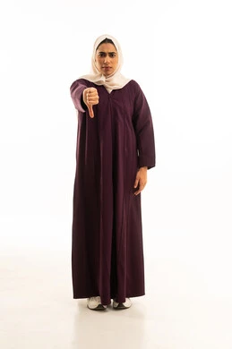 عدم القبول و الرفض و الفشل والخسارة، بورتريه لامرأة عربية خليجية سعودية محجبة ترتدي عباءة  تشير بأصبع الابهام الى الاسفل ، حركات يد تدل على عدم الموافقه و عدم الإعجاب, الشعور بالإنزعاج من شيء ما، الجسم بالطول الكامل, خلفية بيضاء