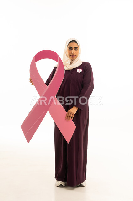الحملة التوعويه بالمرض الخبيث, بورتريه لإمرأة عربية خليجية سعودية محجبة ترتدي العباءة تحمل شعاراليوم العالمي للتوعيه بالكشف المبكر ,الجسم بالطول الكامل, خلفية بيضاء