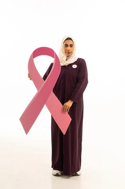 الحملة التوعويه بالمرض الخبيث, بورتريه لإمرأة عربية خليجية سعودية محجبة ترتدي العباءة تحمل شعاراليوم العالمي للتوعيه بالكشف المبكر ,الجسم بالطول الكامل, خلفية بيضاء