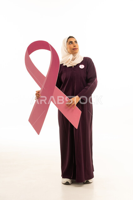 النظر الى شىء ما فى الاعلى, بورتريه لإمرأة عربية خليجية سعودية محجبة ترتدي العباءة و شعار الحملة العالمية لسرطان الثدى, الجسم بالطول الكامل, خلفية بيضاء
