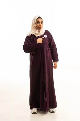 The awareness campaign for malignant diseases, a portrait of a Saudi Gulf Arab woman in a hijab wearing an abaya pointing to the logo of the global breast cancer campaign, full-body, white background.