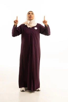 Locating a specific object, expressions of certainty and pinpointing a specific place, a portrait of a smiling Saudi Gulf Arab woman wearing an abaya and the logo of the global breast cancer campaign pointing her index fingers upwards, full-body image, white background.