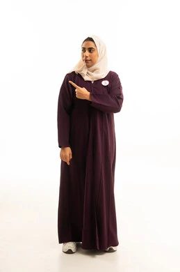 الوقوف باستقامة والاشارة إلى شيء ما، تعابير التأكد و تحديد مكان معين, بورتريه لامرأة عربيه خليجيه سعودية مبتسمة ترتدي العباءة و شعار الحملة العالمية لسرطان الثدى ترفع اصبعها السبابة للاختيار، صورة الجسم بالطول الكامل, خلفية بيضاء