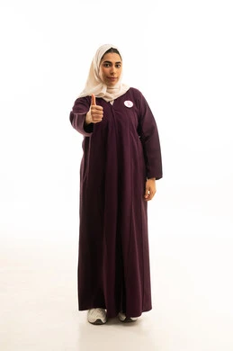 تعابير الموافقة و القبول ,النظر الى الكاميرا بإيماءات السرور, بورتريه لإمرأة عربية خليجية سعودية محجبة ترتدي العباءة و  شعار الحملة العالمية لسرطان ترفع اصبع الابهام للاعلى بعلامة الامتياز و الجودة , الجسم بالطول الكامل, خلفية بيضاء