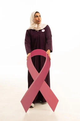 تحدي المرض الخبيث, بورتريه لامرأة عربية خليجية سعودية مبتسمة محجبة ترتدي العباءة البنية  و شعار التوعيه بالكشف المبكر، الحملة التوعويه بالمرض الخبيث، الجسم بالطول الكامل, خلفية بيضاء