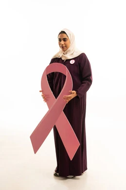 الحملة التوعويه بالمرض الخبيث, بورتريه لامرأة عربية خليجية سعودية مبتسمة محجبة ترتدي العباءة البنية  و شعار التوعيه بالكشف المبكر، الحملة التوعويه بالمرض الخبيث، الجسم بالطول الكامل, خلفية بيضاء