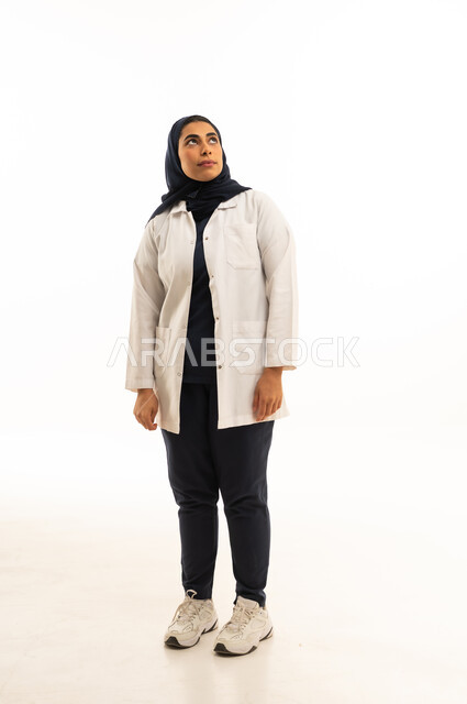 التأمل والنظر للاعلى، الاناقة والاهتمام بالظهر الخارجي، بورتريه  لامرأة عربية خليجية سعودية محجبة ترتدي الزى الكاجوال تنظر الى شىء ما, الجسم بالطول الكامل, خلفية بيضاء