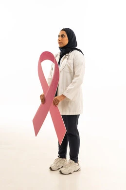 بوتريه من الجانب لامرأة عربية خليجية سعودية محجبة ترتدي الزى الكاجوال تمسك بيديها شعار الحملة العالمية, تقديم المساعدة والدعم من خلال الكشف المبكر عن سرطان الثدي، خلفية بيضاء