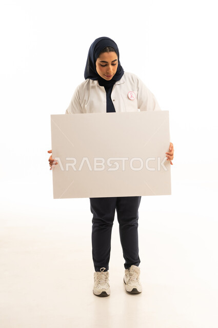 موك اب مستطيل أبيض, بوتريه لامرأة عربية خليجية سعودية محجبة ترتدي الزى الكاجوال و شعار الحملة العالمية لسرطان الثدى تحمل بيدها  لوحة توعوية مستطيلة فارغة, خلفية بيضاء