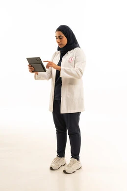 استخدام التقنية الحديثة, بورتريه لامرأة عربية خليجية سعودية محجبة ترتدي الزى الكاجوال و شعار التوعيه بالكشف المبكر لسرطان الثدي تستخدم التابلت، اليوم العالمي للتوعية بالامراض الخبيثة, الجسم بالطول الكامل, خلفية بيضاء