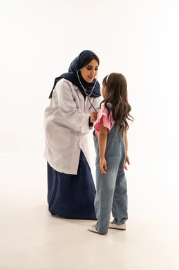 ممارسة مهنة الطب بحرفية تامة , طبيبة قلب عربية خليجية سعودية ترتدي المعطف الطبي الابيض تجري فحصاً دورياً للفتاة الصغيرة , طفلة عربية خليجية سعودية ترتدي الزي الكاجوال تقف امام الطبيبة لاستكمال عملية الفحص , بورتريه خلفية بيضاء, الجسم بالطول الكامل