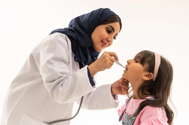 الاطمئنان على صحة الصغار من المهمات الاساسية في هيئة الهلال الاحمر السعودي , طبيبة عربية خليجية سعودية محجبة ترتدي المعطف الطبي الابيض تقوم بقياس درجة حرارة جسد الفتاة الصغيرة , طفلةعربية خليجية سعودية ترتدي الزي الكاجوال تقف امام الطبيبة للتأكد من سلامتها , بورتريه مقرب , خلفية بيضاء
