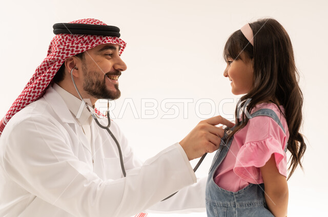 القيام بالفحوصات الدورية بسعادة , طبيب عربي خليجي سعودي يرتدي المعطف الطبي الابيض يستمع بانصات الى نبضات قلب الفتاة الضغبرة , طفلة عربية خليجية سعودية ترتدي الزي الكاجوال تقوم بالاطمئنان على صحة القلب , بورتريه مقرب , خلفية بيضاء