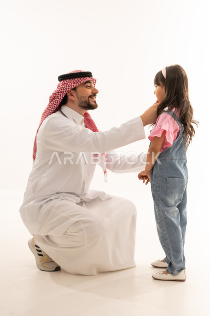 طبيب عربي خليجي سعودي يرتدي المعطف الطبي الابيض يجلس امام القرفصاء الفتاة الصغيرة , ايماءات السعادة و الابتسام , طفلة عربية خليجية سعودية ترتدي الزي الكاجوال تقف امام طبيب الاسنان سعيدة بعد اتمام العلاج , خلفية بيضاء , بورتريه الجسم بالطول الكامل