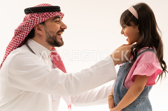 الابتسامة الصافية بعد التاكد من سلامة الاسنان الصغيرة , طبيب عربي خليجي سعودي يشعر بالسعادة بعد انتهاء الفحص الدوري , طفلة عربية خليجية سعودية ترتدي الزي الكاجوال تقف امام الطبيب الكفء بعد اتمام العلاج و الاطمئنان على صحة الفم , بورتريه مقرب , خلفية بيضاء
