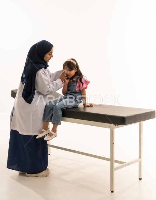 Post-surgical healthcare is required. A Saudi Arabian Gulf Arab female doctor wearing a white medical coat is removing the medical bandage from the girl's eye. A Saudi Arabian Gulf Arab girl dressed in casual attire sits steadily and confidently during the follow-up after the surgery. Portrait with a white background, full-body shot.