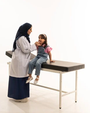 Comprehensive medical examination for young children, a Saudi Gulf Arab girl wearing casual attire sitting on the examination bed in the clinic, a veiled Saudi Gulf Arab doctor wearing a white medical coat measuring the little girl's temperature to ensure her safety, portrait with a white background, full body.