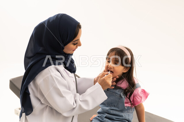 التطعيمات الرئيسية الضرورية للاطفال متاحة مجاناً في هيئة الهلال الاحمر السعودي , طبيبة عربية خليجية سعودية تقوم بتطعيم طفلة صغيرة من الامراض المعدية  , طفلة عربية خليجية سعودية ترتدي الزي الكاجوال تتلقى جرعة التطعيم المحددة و المناسبة لها , بورتريه مقرب , خلفية بيضاء
