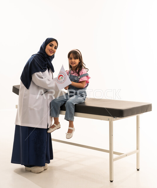 الاستعانة بالاطباء ذوي الخبرة و الكفاءة في هيئة الهلال الاحمر السعودي , طبيبة عربية خليجية سعودية محجبة ترتدي المعطف الطبي الابيض تحمل علم الهيئة ,طفلة عربية سعودية صغيرة تجلس على سرير الكشف , بورتريه خلفية بيضاء ,الجسم  بالطول الكامل