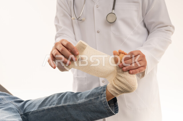 بورتريه مقرب لطبيب هيئة الهلال الاحمر السعودي يمارس العمل باحترافية تامة , طفلة عربية خليجية سعودية ترتدي الزي الكاجوال نائمة على سرير الكشف و ترفع القدم المتألمة , طبيب عربي خليجي سعودي يرتدي المعطف الطبي و يضع الضمادة الطبية للفتاة الصغيرة , خلفية بيضاء