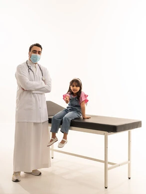 طبيب عربي خليجي سعودي يرتدي الكمامة و المعطف الطبي الابيض يقف بشموخ بعد انتهاء الفحص الطبي , طفلة عربية خليجية سعودية ترفع اصبع الابهام للاعلى علامة على الجودة و اتمام المهمة , بورتريه خلفية بيضاء , الجسم بالطول الكامل