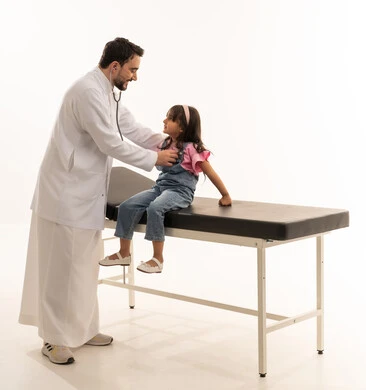 All important specialties are available at the Saudi Red Crescent Authority, distinguished competencies, an Arab Gulf Saudi doctor wearing a white medical coat holding a stethoscope and listening attentively to heartbeats, an Arab Gulf Saudi girl wearing casual attire leaning on the examination bed to be examined, portrait with a white background, full-body.