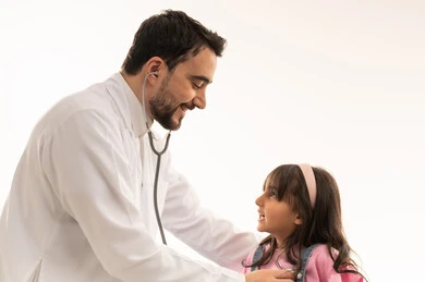 العناية بالقلوب الصغيرة مهمة أساسيية في هيئة الهلال الاحمر السعودي , طبيب قلب عربي خليجي سعودي يرتدي المعطف الابيض الطبي يسمع نبضات قلب الطفلة  , طفلة عربية خليجية سعودية ترتدي الزي الكاجوال تجلس على سرير الكشف لاتمام عملية الفحص , بورتريه مقرب , خلفية بيضاء