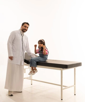 Portrait with a white background, full-body, a Gulf Arab Saudi girl sitting on the examination bed in the clinic, raising her hands in joy at the end of her treatment journey. An Arab Gulf Saudi doctor wearing a white medical coat stands next to the girl, showing gestures of happiness and joy, looking at the camera.